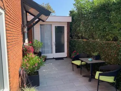 a patio with a table and chairs and a door at Sunny Place in Zandvoort