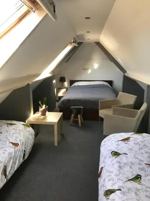 a attic bedroom with two beds and a couch and a table at Aan de Wiericke in Driebruggen