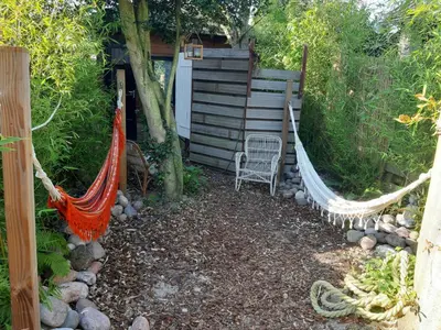 a hammock in a garden next to a cabin at Ecolodge de Parel Schoorl in Schoorl