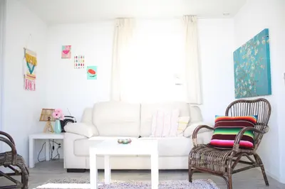 a living room with a white couch and chairs at Chalet Charlee in IJmuiden
