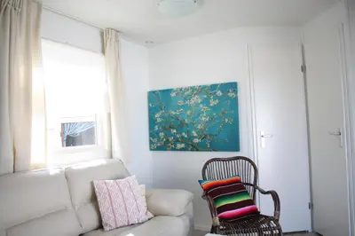 a living room with a white couch and a chair at Chalet Charlee in IJmuiden