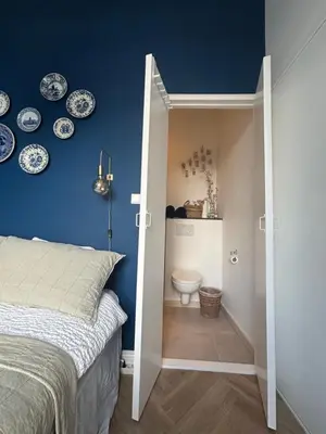 a bedroom with a bed and a toilet and plates on the wall at Lovely small apartment in 'De Pijp' in Amsterdam