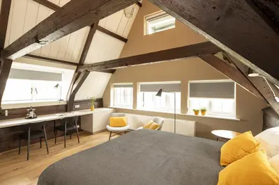 a loft bedroom with a bed and a desk and chairs at Saenliefde in Wormer