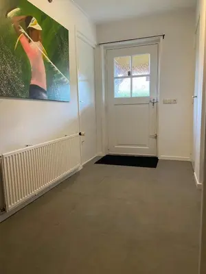 an empty room with a painting on the wall and a door at Familiehuis Achter de Duijnhoeve Bakkum in Zuidbakkum