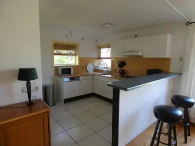 a kitchen with white cabinets and a counter top at Familiehuis Achter de Duijnhoeve Bakkum in Zuidbakkum