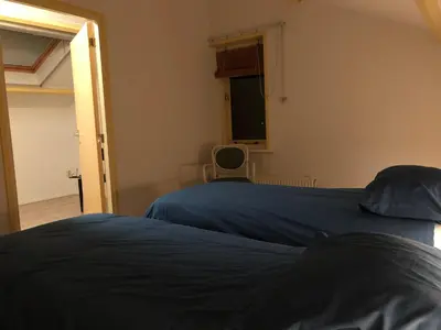 a bedroom with two beds and a window at Familiehuis Achter de Duijnhoeve Bakkum in Zuidbakkum