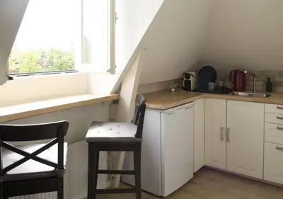 a kitchen with white cabinets and a table and a chair at Miriam's Suite Amsterdam in Amsterdam
