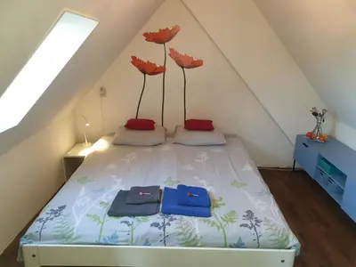 a bedroom with a bed with red flowers on it at Bed & Bye Schiphol in Badhoevedorp