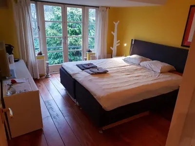 a bedroom with a large bed and a large window at Bed & Bye Schiphol in Badhoevedorp