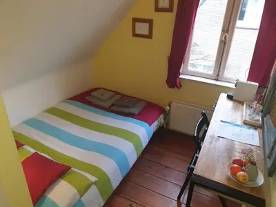 a small bedroom with a bed and a table at Bed & Bye Schiphol in Badhoevedorp