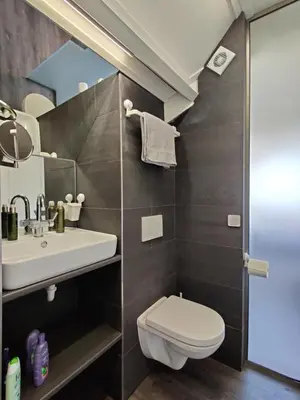 a bathroom with a white toilet and a sink at B&B Be Our Guest in Sint Maarten