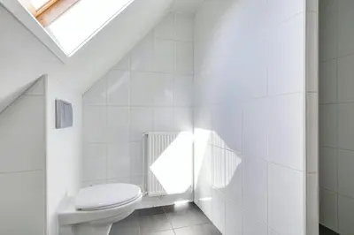 a white bathroom with a toilet and a skylight at Vakantiewoning Seaewald in Zeewolde