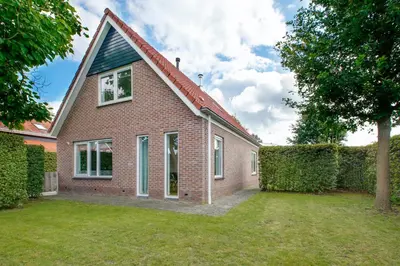 a red brick house with a grass yard at Vakantiewoning Seaewald in Zeewolde