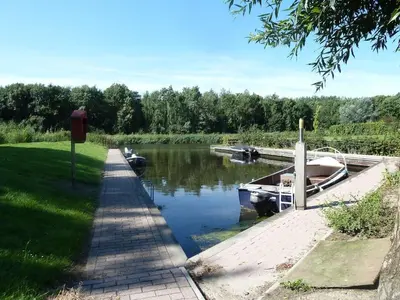 a boat is docked at a dock on a river at Vakantiewoning Seaewald in Zeewolde