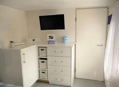 a room with a dresser with a tv on the wall at Ferienpark Vislust Haus De Graaf Niederlande Ijsselmeer in Wervershoof