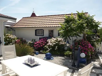 a white table and chairs in front of a house at Ferienpark Vislust Haus De Graaf Niederlande Ijsselmeer in Wervershoof