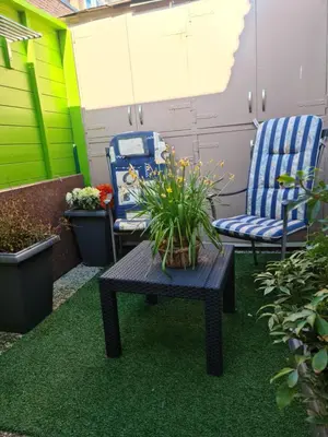 a patio with two chairs and a table with a plant at Tamar in Katwijk aan Zee
