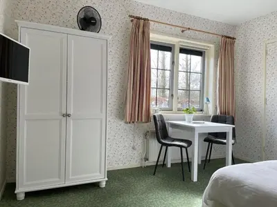 a bedroom with a white cabinet and a table and chairs at Bed & Breakfast Pax Tibi in Reeuwijk