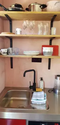 a kitchen counter with a sink and glasses on shelves at Jabaki Red Studio in Hoofddorp