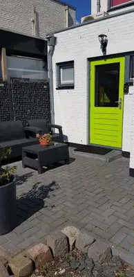 a yellow door on a building with a patio at JaBaKi Green Studio in Hoofddorp