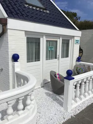 a white house with a white fence and a dog at little ibiza in Zandvoort