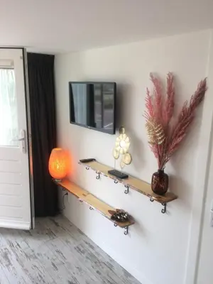 a room with a tv and a shelf on the wall at little ibiza in Zandvoort