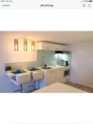 a kitchen with white cabinets and a sink and counters at little ibiza in Zandvoort