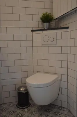 a white toilet in a white tiled bathroom at Cosy Casa in Egmond aan Zee