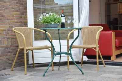 two chairs and a glass table on a patio at Cosy Casa in Egmond aan Zee
