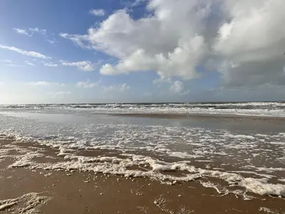a sandy beach with waves in the ocean at Cosy Casa in Egmond aan Zee