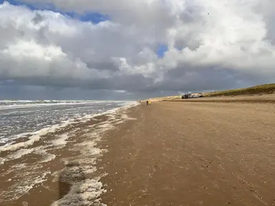a sandy beach with a cloudy sky and the ocean at Cosy Casa in Egmond aan Zee