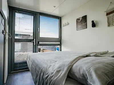 a bedroom with a large bed and a large window at Harbour Lodge at Uitgeestermeer View in Uitgeest