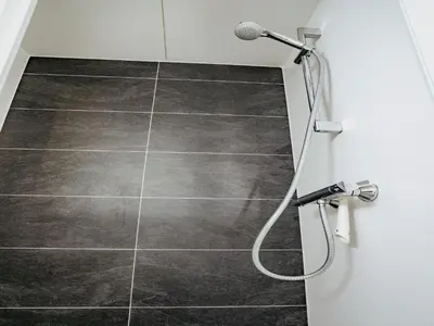 a bathroom with a shower head and a tile floor at Harbour Lodge at Uitgeestermeer View in Uitgeest