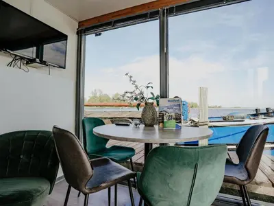 a dining room with a table and green chairs at Harbour Lodge at Uitgeestermeer View in Uitgeest