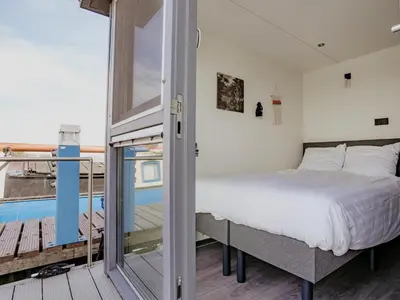 a bedroom with a bed and a balcony at Harbour Lodge at Uitgeestermeer View in Uitgeest