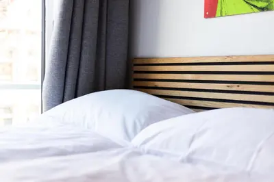 a bed with a white pillow and a window at Weber Hotel 117 in Amsterdam