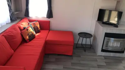 a red couch in a living room with a tv at Luxe Chalet op camping Duindoorn, IJmuiden aan Zee, in de buurt van F1 circuit Zandvoort en Bloemendaal op loopafstand strand in IJmuiden