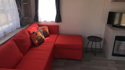 a red couch in a living room with a window at Luxe Chalet op camping Duindoorn, IJmuiden aan Zee, in de buurt van F1 circuit Zandvoort en Bloemendaal op loopafstand strand in IJmuiden