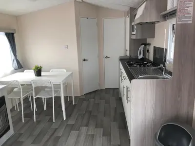 a small kitchen with a table and a stove at Luxe Chalet op camping Duindoorn, IJmuiden aan Zee, in de buurt van F1 circuit Zandvoort en Bloemendaal op loopafstand strand in IJmuiden