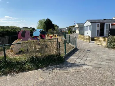 a playground with a slide and a fence at Luxe Chalet op camping Duindoorn, IJmuiden aan Zee, in de buurt van F1 circuit Zandvoort en Bloemendaal op loopafstand strand in IJmuiden