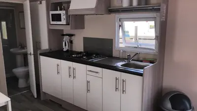 a small kitchen with a sink and a window at Luxe Chalet op camping Duindoorn, IJmuiden aan Zee, in de buurt van F1 circuit Zandvoort en Bloemendaal op loopafstand strand in IJmuiden