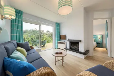 a living room with a blue couch and a fireplace at Center Parcs Zandvoort beach in Zandvoort