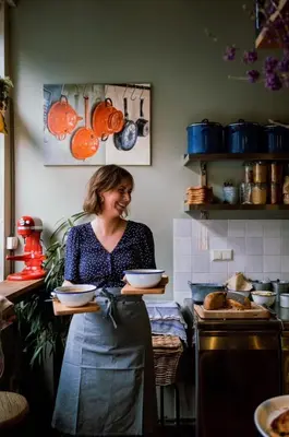 a woman in a kitchen holding a tray of bowls at Logement Petit Beijers in Utrecht
