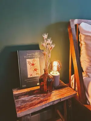 a table with a vase with flowers and a book and a candle at Logement Petit Beijers in Utrecht