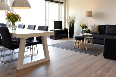 a living room with a table and chairs and a couch at Residence Le Mistral in Noordwijk aan Zee