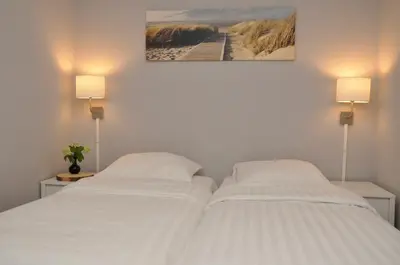 two twin beds in a room with two lamps at Residence Le Mistral in Noordwijk aan Zee
