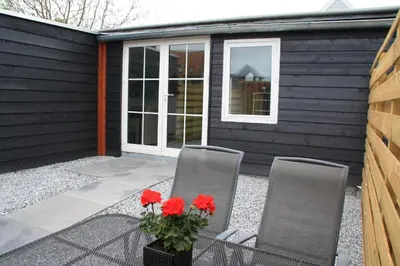 two chairs and a vase with red flowers on a patio at Bed & Breakfast Aalsmeer in Aalsmeer