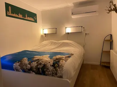 a bed in a room with two lights on the wall at Bed & Breakfast Aalsmeer in Aalsmeer