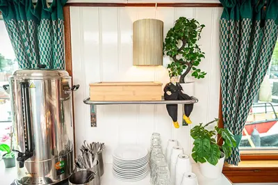 a kitchen counter with a shelf with dishes and plants at Amsterdam Hotelboat in Amsterdam