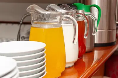 a glass jug of orange juice next to a stack of plates at Amsterdam Hotelboat in Amsterdam